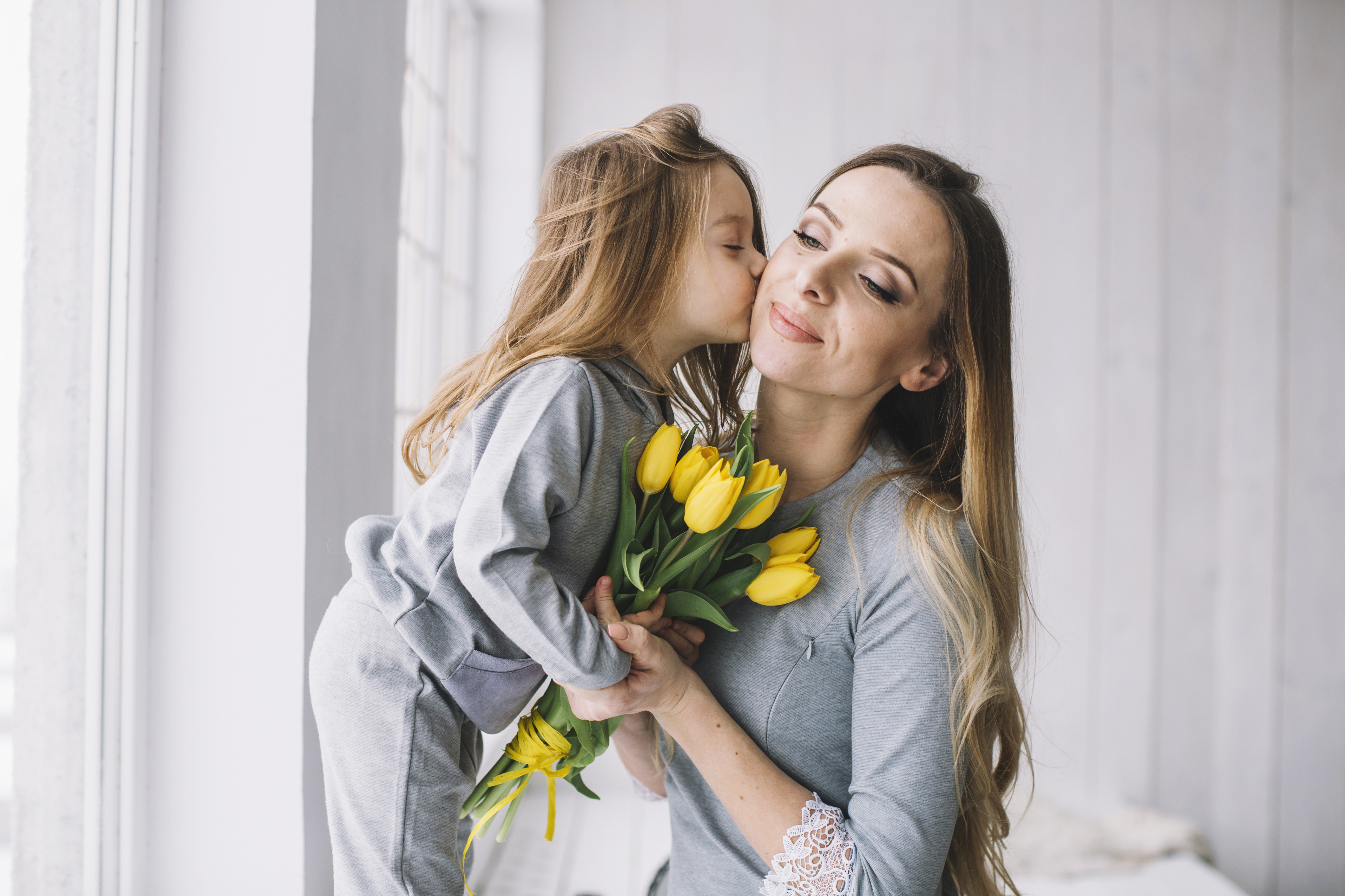 Праздник посвященный маме. Мама целует дочь. Девочка целует маму. День матери в США. Мама с дочкой цветы.